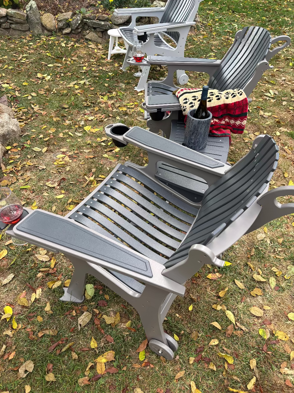 Gray outdoor chairs on a grassy area with fallen leaves
